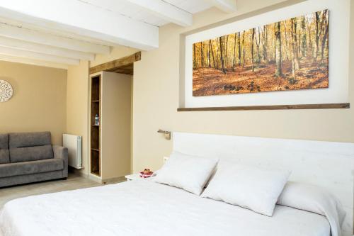 1 dormitorio con cama blanca y sofá en Habitacions Plaça Major, en Santa Pau