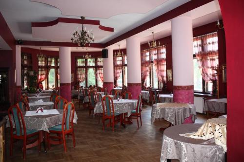 a dining room with tables and chairs and windows at Ośrodek Wypoczynkowy Rapsodia in Krynica Zdrój