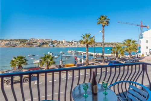 d'un balcon avec une table et des chaises et une vue sur le port. dans l'établissement Harbour Lights seafront 2 bedroom apartments with panoramic sea views - by Getawaysmalta, à San Pawl il-Baħar