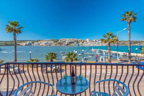 un tavolo e sedie su un balcone con vista sull'acqua di Harbour Lights seafront 2 bedroom apartments with panoramic sea views - by Getawaysmalta a San Pawl il-Baħar
