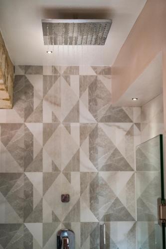 a bathroom with a geometric tile wall at Residenza Vranas Boutique Hotel in Chania Town