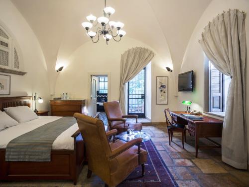 a bedroom with a bed and a desk and chairs at The American Colony Hotel - Small Luxury Hotels of the World in Jerusalem