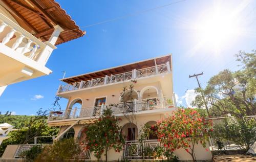 a large white building with balconies and flowers at Villa Eleni - Maisonette with Ocean panorama terrace in Alikanas