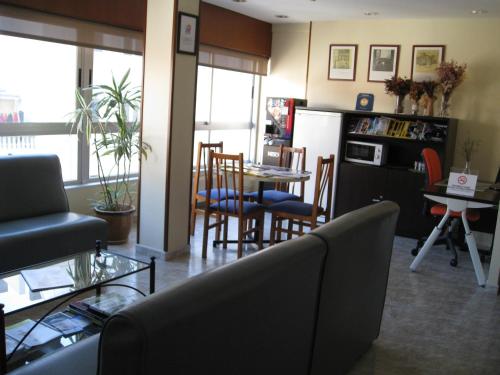 cocina y sala de estar con mesa y sillas en Hostal Roma, en A Coruña