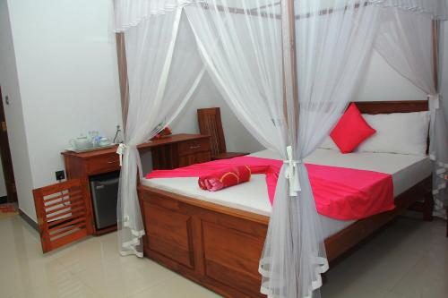 a bedroom with a canopy bed with red pillows at Maduranga n Guest in Mirissa