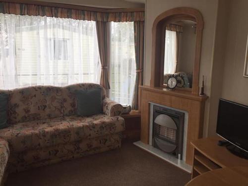a living room with a couch and a fireplace at 8 BERTH CARAVAN TP49 ON THE GOLDEN PALM CHAPEL ST LEONARDS in Skegness