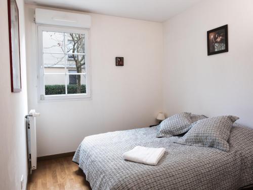 a white bedroom with a bed and a window at Family Travel Paris 2 in Bussy-Saint-Georges