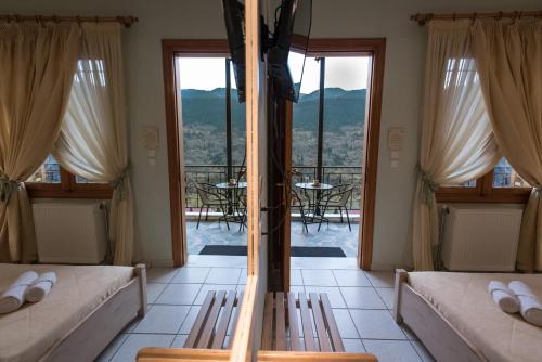a room with two beds and a balcony with a table at Το Ηλιοβασίλεμα in Méga Khoríon