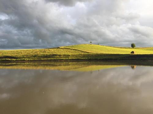 a grassy hill next to a body of water at Siedlisko Pod Strzechą in Wólka