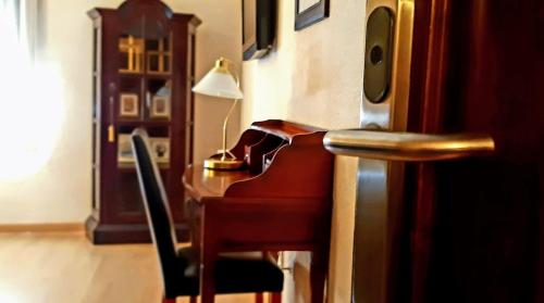 a room with a desk with a piano and a lamp at Hostal Rural Moratín in Pastrana