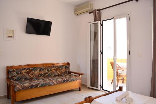 Zimmer mit einem Bett und einem TV an der Wand in der Unterkunft Raph's Studios-Apts By The Sea in Agia Marina