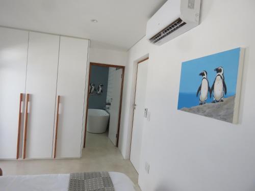 赫曼努斯Troon Beach Cottage Hermanus的墙上有两只企鹅的卧室