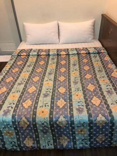 a bed with a colorful quilt on it at Good Ground Hotel Tainan in Tainan
