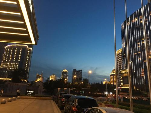 a city skyline at night with cars parked in a parking lot at Qingdao Elegant Central Apartment in Qingdao