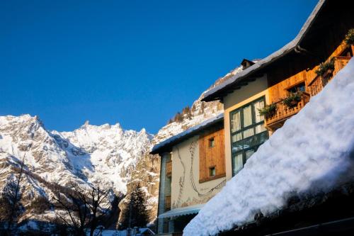 a building covered in snow with mountains in the background at Gran Baita Hotel & Wellness in Courmayeur