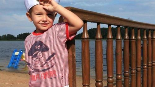 a young boy standing next to a railing near the water at Pensjonat Teresa in Marcinowa Wola