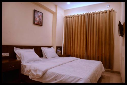 a bedroom with a large bed and a curtain at Malhar Grand in Jejūri