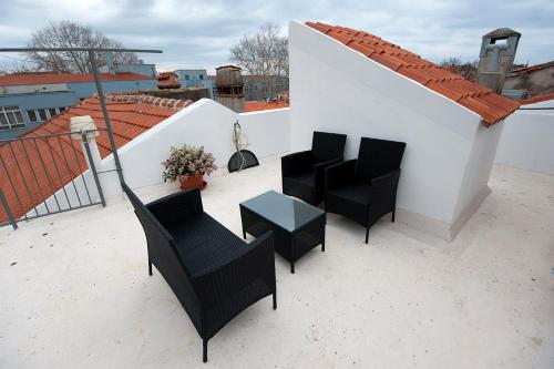a patio with chairs and a table on a roof at Rooms & Apartments 72 in Zadar