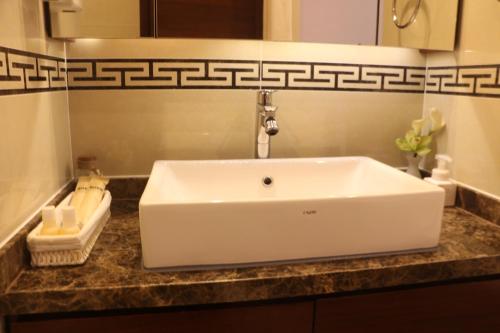 a white sink in a bathroom with a counter at Qingdao Elegant Central Apartment in Qingdao