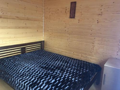a room with a bed in a wooden wall at Sadyba Domashniy zatyshok in Pilipets