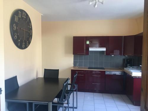 une cuisine avec une table et une horloge au mur dans l'établissement La trinite, à Gérardmer