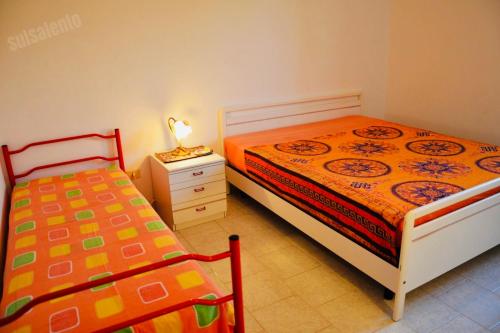 リド・マリーニにあるCasa Vacanza BERMUDAのベッドルーム1室(ベッド2台、ナイトスタンドのランプ付)