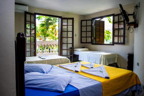 a room with two beds and two windows at Beira Mar in Ubatuba