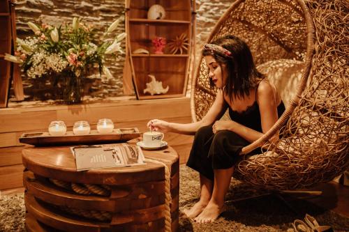 a woman sitting in a wicker chair drinking coffee at Hotel Pleamar in Puerto de Vega