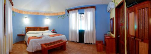 a bedroom with blue walls and a bed with a bench at Hotel Villas Kin Ha in Palenque