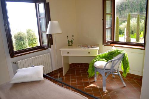 a bedroom with a chair and a desk and windows at Monte A Pescia in Pescia