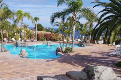 una piscina con palmeras y un complejo en Apartamentos Playa de Los Roques en Los Realejos