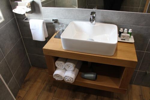 a bathroom with a sink and towels on a shelf at Villa Aruba & Private SPA Suites in Keszthely
