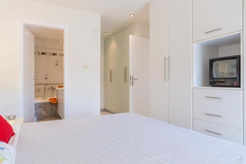 a white bedroom with a bed and a tv at Santa Barbara Garden and Pool Home in Marathón