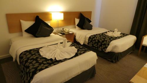 a hotel room with two beds with black and white sheets at Amman Airport Hotel in Al Qasţal