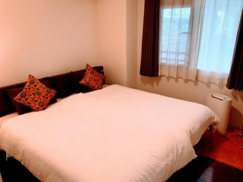 a white bed in a room with a window at Condo Coral Resort Okinawa in Fuzuchi