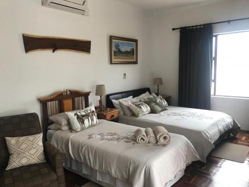 1 dormitorio con 2 camas, silla y ventana en Towerzicht Guest House, en Ladismith