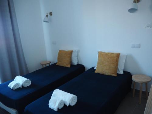 two beds in a room with blue sheets and pillows at Casa AUGUSTA in Lagos