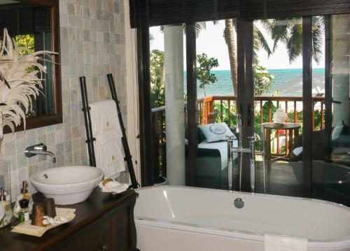 a bathroom with a tub and a view of the ocean at Dhevatara Beach Hotel in Grand'Anse Praslin