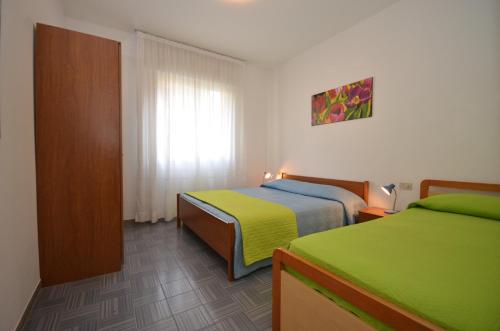 a hotel room with two beds and a window at Appartamenti Villa Angela in Bibione