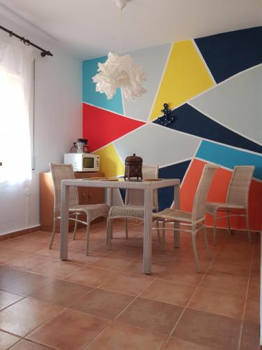 un comedor con mesa, sillas y una pared colorida en Isla Canela Natura, en Isla Canela