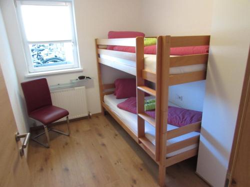 ein Schlafzimmer mit Etagenbetten mit einem Stuhl und einem Fenster in der Unterkunft Apart Schranz in Grins