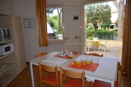 una cocina con una mesa blanca con sillas y una ventana en Villaggio San Siro, en Bibione