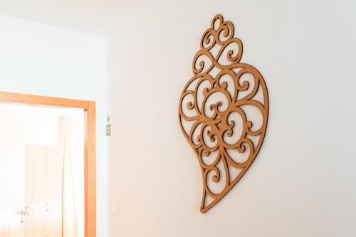 a wooden heart hanging on a white wall at Soldouro Guesthouse in Aveiro