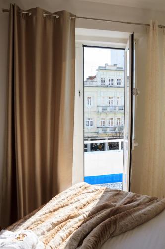 a bedroom with a bed and a large window at Soldouro Guesthouse in Aveiro