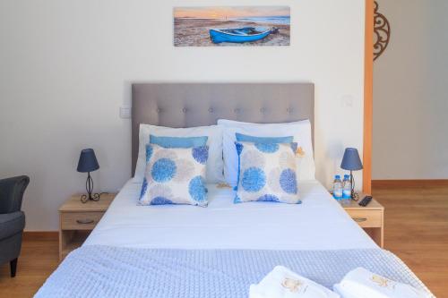 a bedroom with a bed with blue and white pillows at Soldouro Guesthouse in Aveiro