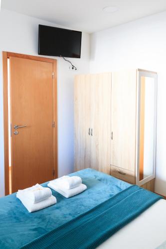 a bedroom with a blue bed with two towels at Soldouro Guesthouse in Aveiro