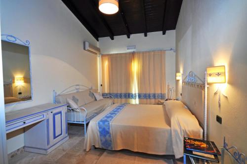 una camera con letto, lavandino e specchio di Hotel Corsaro Nero a Portu Maga