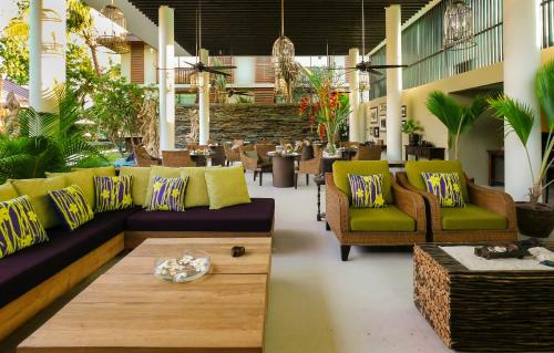 a lobby with couches and a table and chairs at Dhevatara Beach Hotel in Grand'Anse Praslin