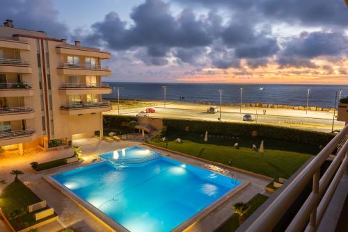 a swimming pool in front of a building with the ocean at BARRAMARES 3 in Furadouro