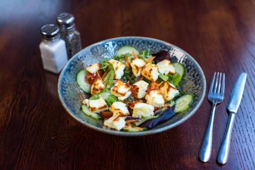 a bowl of salad with tofu and cucumbers on a table at The Old Vine in Winchester